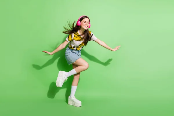 Foto de tamaño completo de funky feliz joven danza buen humor escuchar música aislada en el fondo de color verde — Foto de Stock