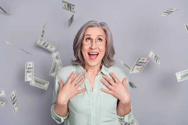 Foto di felice scioccato allegro stupito donna matura eccitato con soldi volanti isolato su sfondo di colore grigio — Foto Stock