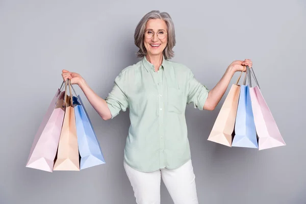 Photo de mature souriant gai belle femme shopaholic hold sacs à provisions isolés sur fond de couleur grise — Photo