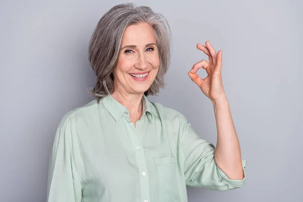 Retrato de atractiva mujer de pelo gris alegre mostrando anuncio ok-signo de acuerdo aislado sobre fondo de color pastel gris —  Fotos de Stock