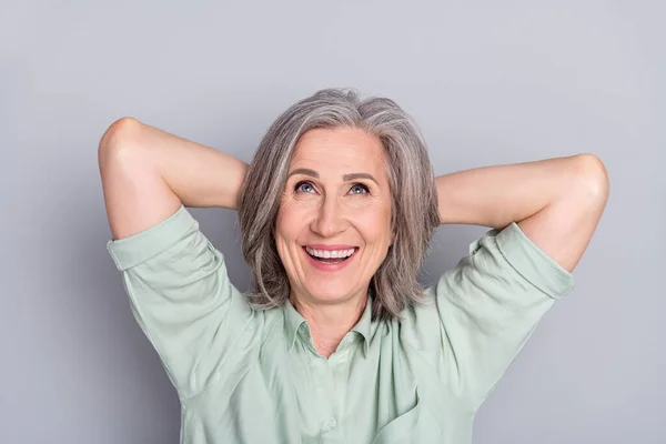 Foto de feliz alegre soñadora sonriente mujer madura buscar copyspace relajante aislado sobre fondo de color gris — Foto de Stock