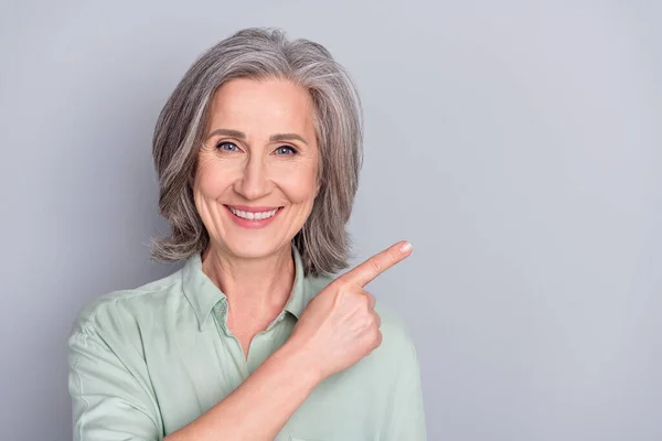 Close-up retrato de atraente alegre mulher de cabelos grisalhos demonstrando anúncio espaço cópia isolado sobre fundo de cor pastel cinza — Fotografia de Stock