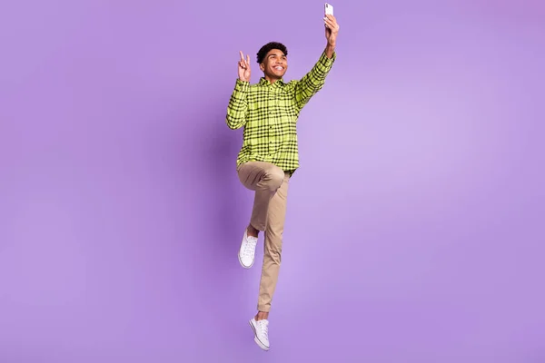 Lunghezza intera dimensione del corpo di giovane salto alto prendendo selfie mostrando v-segno sorridente isolato su sfondo di colore viola pastello — Foto Stock