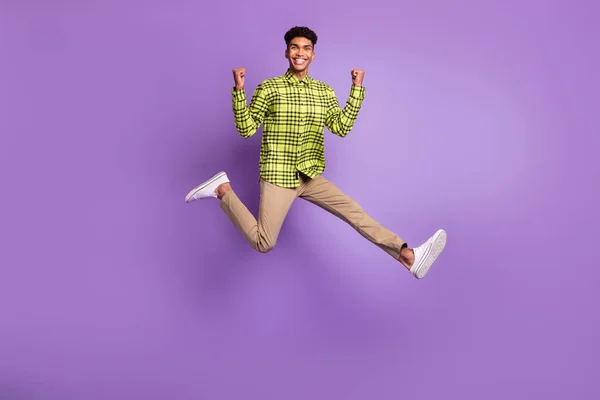 Lunghezza intera dimensione del corpo di giovane salto alto ridere gesticolando come vincitore sorridente isolato su sfondo di colore viola pastello — Foto Stock