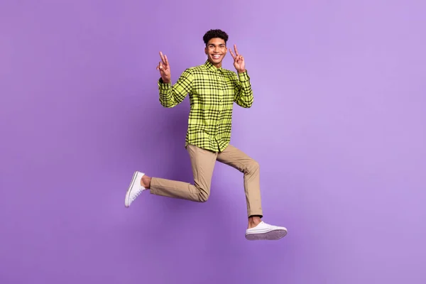 Lunghezza intera dimensione del corpo di giovane salto alta esecuzione veloce sorridente mostrando gesto v-segno isolato su sfondo di colore viola pastello — Foto Stock