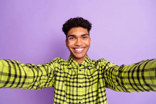 Zelfportret van een knappe, vrolijke brunet in een geruit hemd, geïsoleerd over een paarse achtergrond. — Stockfoto