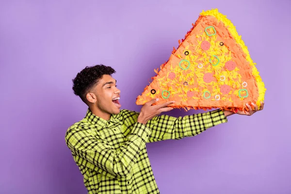 Foto del lado del perfil del atractivo hombre afroamericano comer papel piñata pizza grande aislado sobre fondo de color violeta —  Fotos de Stock