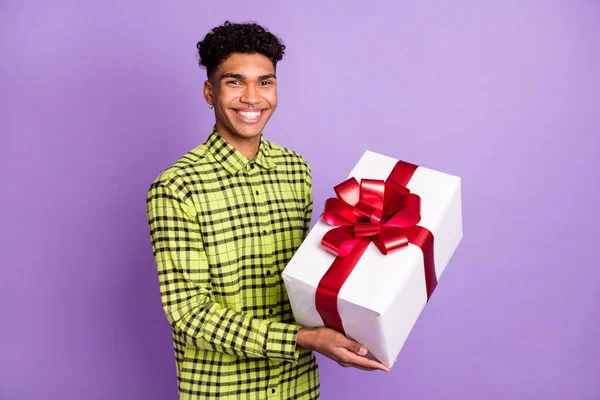 Portrait d'attrayant brunet gai gars tenant dans les mains cadeau festal félicitations isolé sur fond violet couleur pourpre — Photo