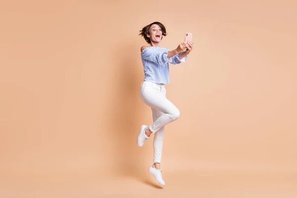 Pleine longueur photo de jeune fille excitée heureux sourire positif saut faire selfie record vidéo blogueur isolé sur fond de couleur beige — Photo