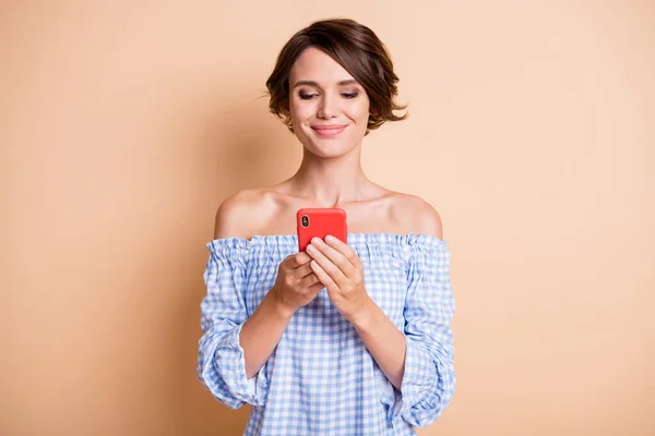 Pozitif kadının iki eliyle telefon tutarken çekilmiş fotoğrafı. Pastel bej renkli arka planda izole edilmiş. — Stok fotoğraf