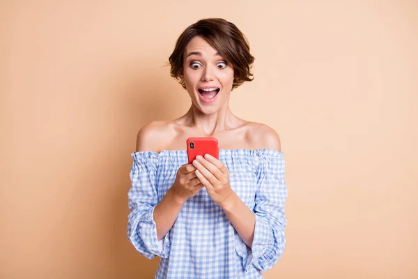 Foto ritratto di impressionato urlando ragazza che tiene il telefono in due mani isolate su sfondo color beige pastello — Foto Stock
