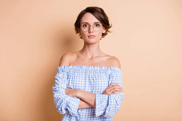 Foto retrato de una mujer seria con los brazos cruzados usando gafas aisladas sobre fondo de color beige pastel —  Fotos de Stock