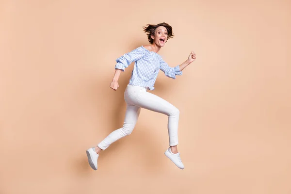 Profil portret szalonej dziewczyny biegnącej z krzykiem skacząc odizolowany na pastelowym beżowym tle — Zdjęcie stockowe