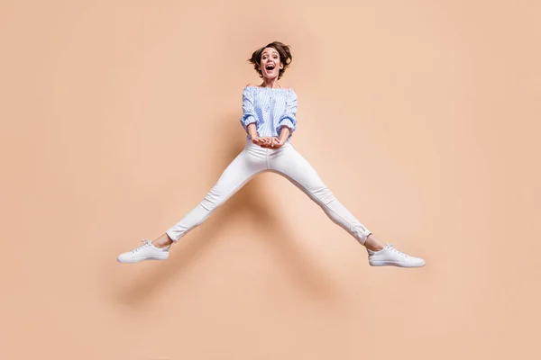 Full längd kroppsstorlek syn på vinröd glad glad flicka hoppa med roliga långa ben isolerade över beige pastell färg bakgrund — Stockfoto