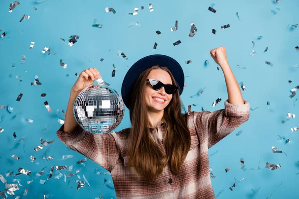 Foto av ung glad glad glad positiv flicka höja knytnävarna i seger hålla disco boll bära solglas isolerad på blå färg bakgrund — Stockfoto