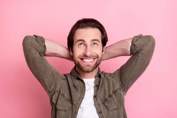 Fotografie atraktivní zasněný chlap oblečený hnědá košile s úsměvem hledá prázdný prostor zbraně za hlavou izolované růžové barvy pozadí — Stock fotografie