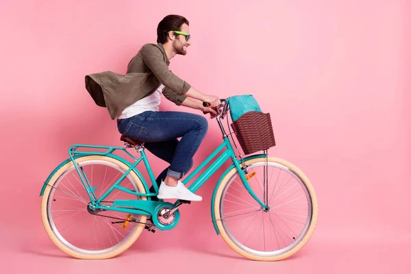 Full length body size profile side view of attractive cheerful guy riding bike isolated over pink pastel color background — Stock Photo, Image