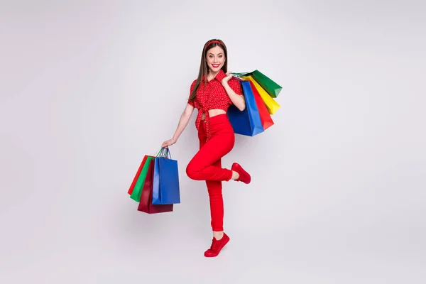 Φωτογραφία της όμορφης κυρίας κρατήσει πολλά πακέτα αυξήσει το πόδι φορούν κόκκινο διάστικτο παντελόνι μπλούζα υποδήματα απομονωμένο γκρι χρώμα φόντο — Φωτογραφία Αρχείου
