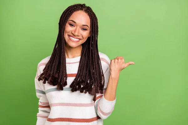 Foto av ung afro flicka glad positiv leende peka tumme tomt utrymme annons föreslå isolerad över grön färg bakgrund — Stockfoto
