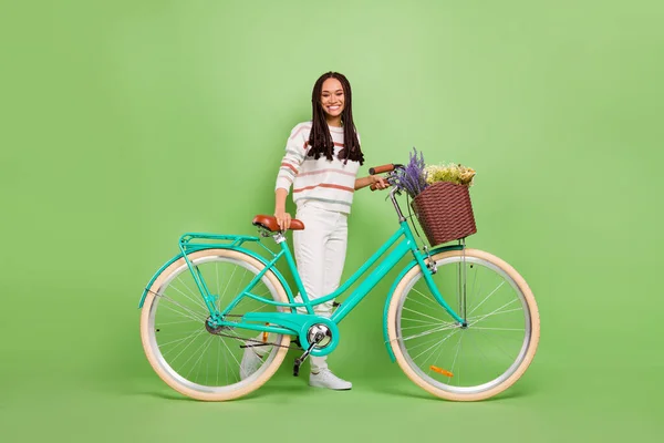 Foto de longitud completa de la joven afro chica feliz sonrisa positiva paseo en bicicleta aislado sobre fondo de color verde — Foto de Stock