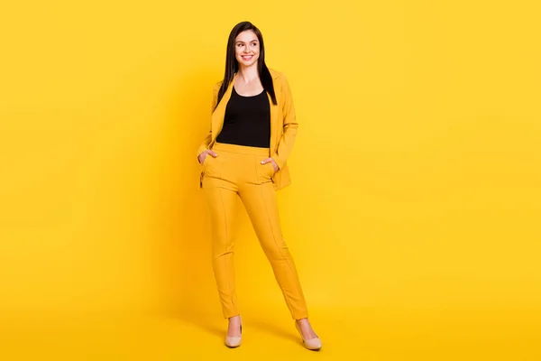 Plná délka fotografie mladé atraktivní ženy šťastný pozitivní úsměv sebevědomé ruce v kapse izolované přes žluté barvy pozadí — Stock fotografie