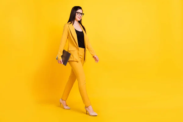 Foto de brillante encantadora dama vestida chaqueta formal sonriendo caminando sosteniendo dispositivo moderno espacio vacío aislado color amarillo fondo —  Fotos de Stock