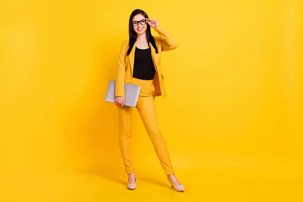Фото довольно милой молодой женщины носить официальный пиджак руки очки держа современный гаджет улыбаясь изолированный желтый цвет фона — стоковое фото