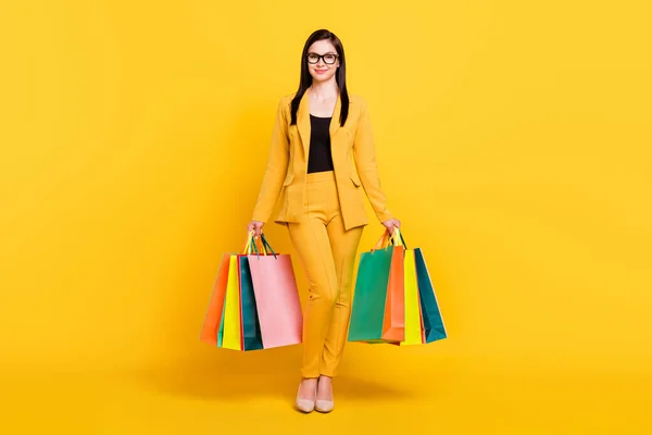 Фотографія молодої привабливої жінки щаслива позитивна посмішка тримає продаж торговельних пакетів ізольовано на жовтому кольоровому фоні — стокове фото
