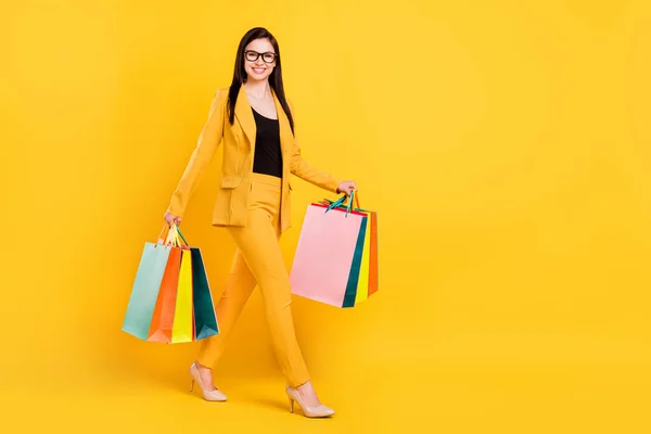 Pleine taille photo de belle millénaire jeune dame tenir des sacs aller porter des lunettes costume jaune isolé sur fond de couleur vive — Photo