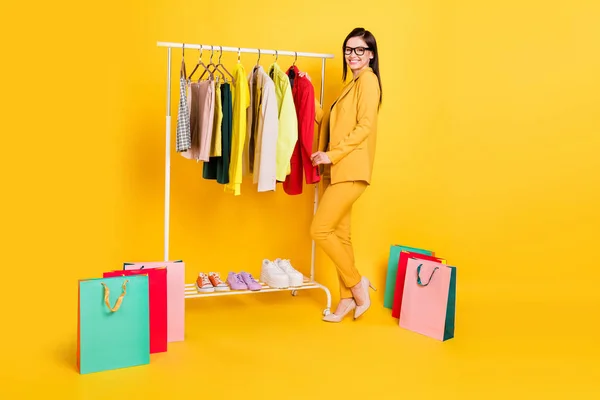 Foto de perfil de tamaño completo de agradable dama milenaria con bolsos eligió paño desgaste gafas traje stilettos en garderobe aislado sobre fondo amarillo — Foto de Stock