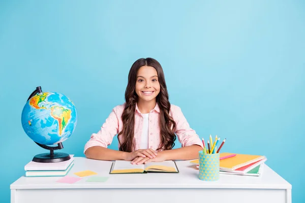 Foto de joven alegre buen humor chica positiva sentarse cámara de escritorio haciendo tarea aislado sobre fondo de color azul — Foto de Stock