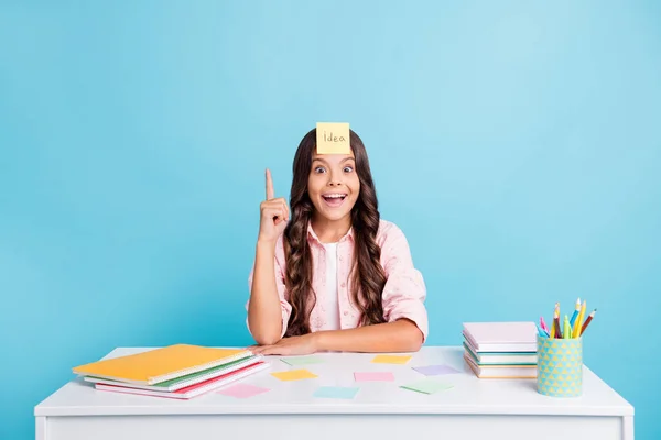 Porträtt av rolig flicka finger direkt upp otrolig reaktion sitter i klassrummet isolerad på blå färg bakgrund — Stockfoto