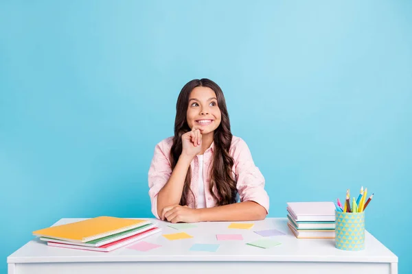 Foto av glada charmiga skolan flicka finger på hakan ser intresserad tomt utrymme isolerad på blå färg bakgrund — Stockfoto