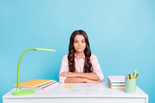 Foto av charmig elev sitter vikta händer copybook anteckningsbok lampa på skrivbordet isolerad på blå färg bakgrund — Stockfoto