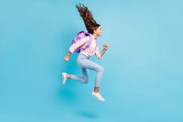 Foto lateral de perfil de tamanho completo da jovem menina alegre sorridente feliz com salto de cabelo marrom isolado no fundo de cor azul — Fotografia de Stock