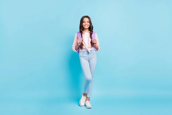 Foto de tamaño completo de joven encantadora bonita sonrisa positiva colegiala desgaste mochila aislada sobre fondo de color azul — Foto de Stock