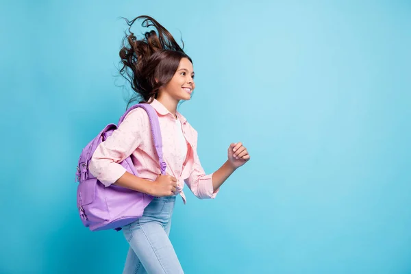 Profiel zijkant foto van jong vrolijk goed humeur lachend meisje met vliegend haar ga naar school geïsoleerd op blauwe kleur achtergrond — Stockfoto