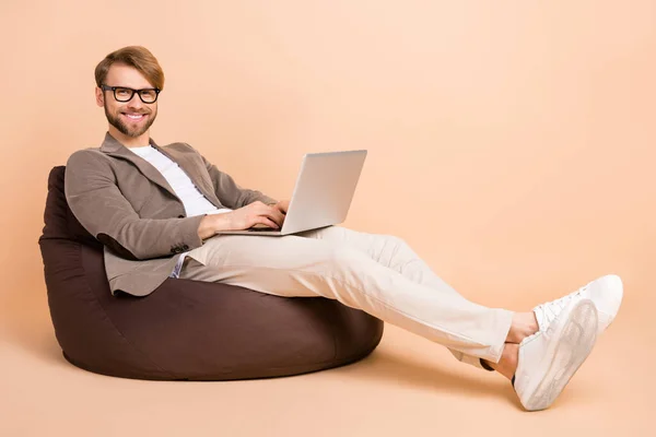 Foto de tamaño completo de empresario atractivo feliz positivo en gafas de trabajo en el ordenador aislado sobre fondo de color beige —  Fotos de Stock