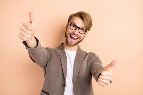 Фото оптимистичного светлых волос мужчина показать большой палец вверх носить очки серый пиджак изолированы на бежевом фоне — стоковое фото