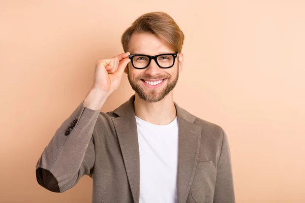 Foto de confiante encantador jovem cavalheiro vestido blazer braço óculos sorrindo isolado cor bege fundo — Fotografia de Stock