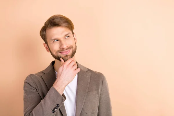 Foto di affascinante riflessivo ragazzo indossare giacca braccio mento cercando spazio vuoto sorridente isolato colore beige sfondo — Foto Stock