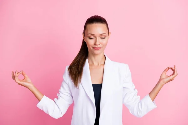 Foto de linda mujer joven pacífica vestida de chaqueta blanca practicando yoga aislado pastel color rosa fondo —  Fotos de Stock