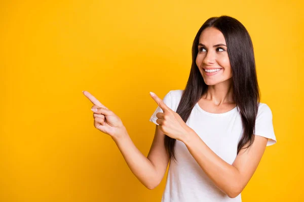 Foto di bella affascinante giovane donna vestita bianca t-shirt cercando indicando spazio vuoto isolato colore giallo sfondo — Foto Stock