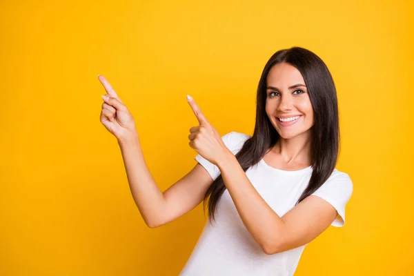 Foto de brillante adorable joven dama usar camiseta blanca apuntando dos dedos espacio vacío aislado color amarillo fondo — Foto de Stock