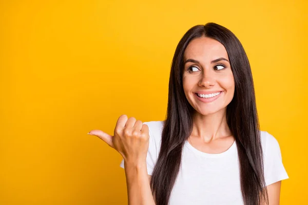 Retrato fotográfico de una chica divertida con una camiseta blanca que muestra el pulgar en blanco sonriendo aislado sobre un fondo de color amarillo vivo — Foto de Stock