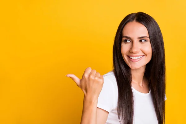 Retrato fotográfico de una chica divertida con una camiseta blanca que muestra el pulgar en blanco sonriendo aislado sobre un fondo de color amarillo vivo — Foto de Stock