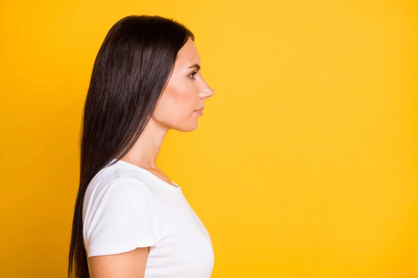 Zijprofiel foto portret van brunette meisje in t-shirt kijken naar lege ruimte met ernstige gezicht geïsoleerd op felgele kleur achtergrond — Stockfoto