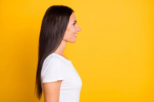 Foto de perfil lateral retrato de chica morena en camiseta mirando el espacio vacío sonriendo aislado sobre fondo de color amarillo vivo —  Fotos de Stock