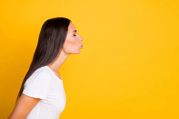 Zijprofiel foto portret van brunette meisje in t-shirt verzenden lucht kus geïsoleerd op levendige gele kleur achtergrond met lege ruimte — Stockfoto
