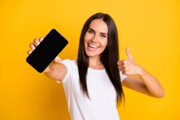 Foto porträtt av suddig ung flicka som visar mobiltelefon display tomt utrymme visar som tecken isolerad på levande gul färg bakgrund — Stockfoto